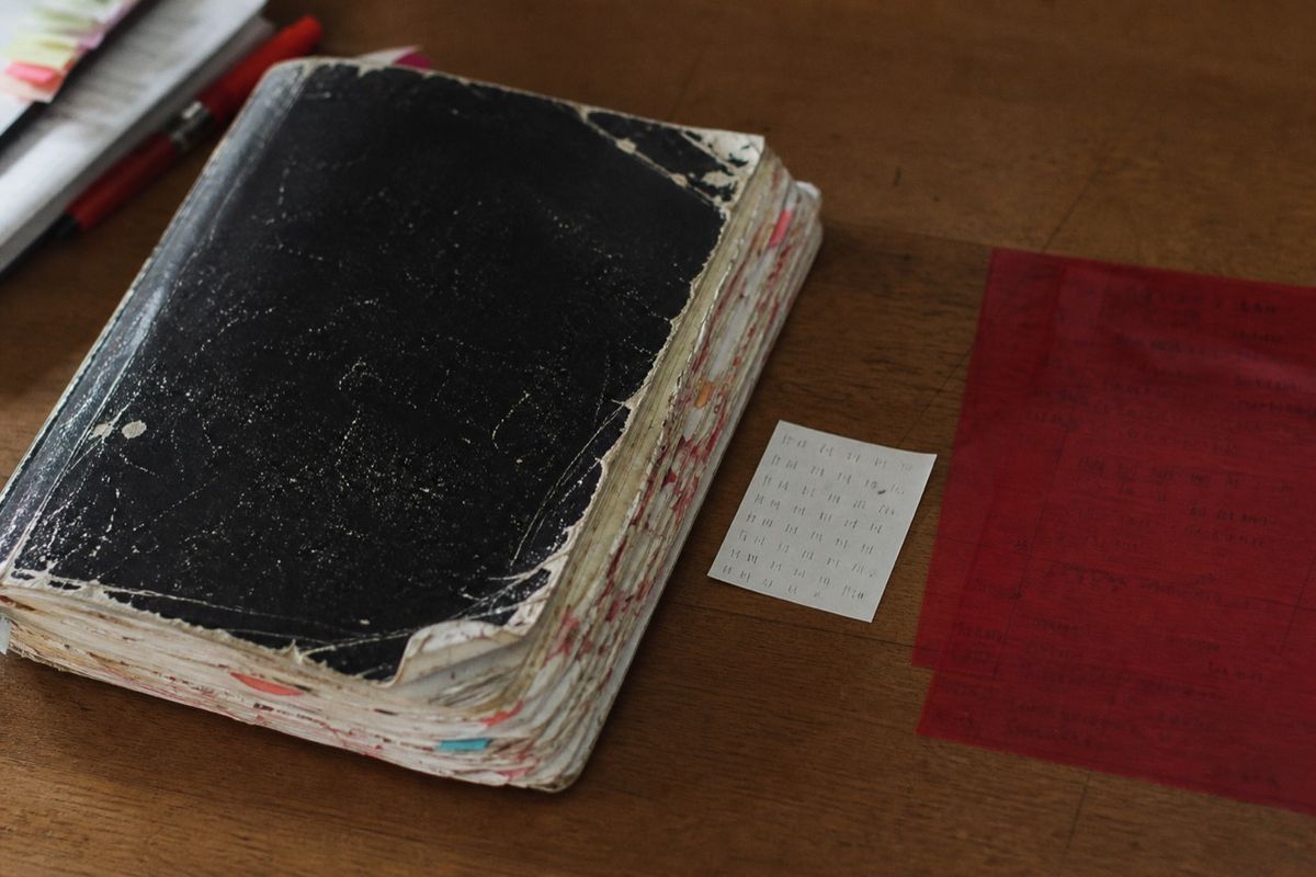 背表紙が割れ、付箋と書き込みで膨らんだ一問一答の問題集。横に周回数を数えた紙と赤シート